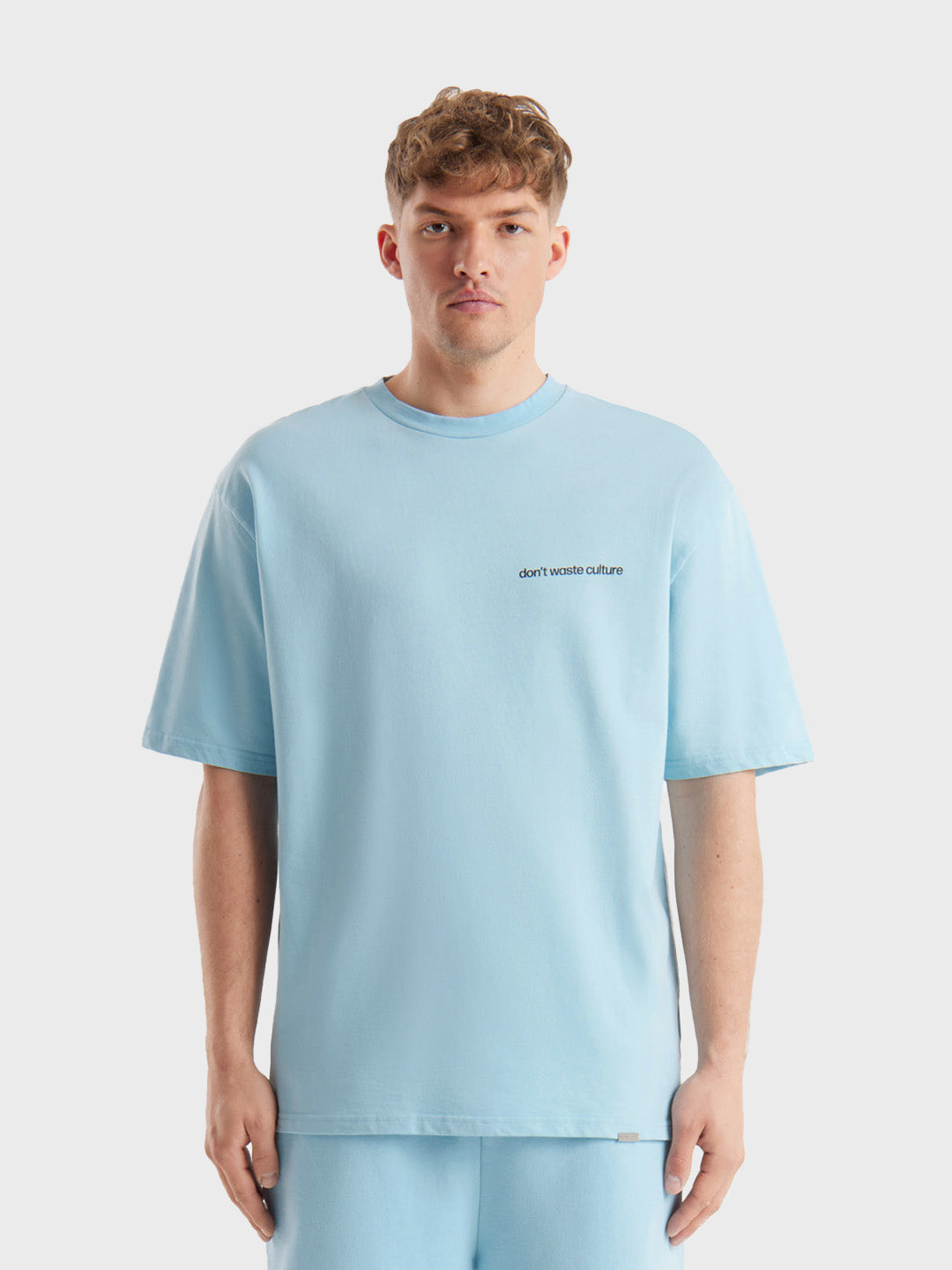 Model draagt Cleo T-shirt in light blue, met kleine borstbranding
