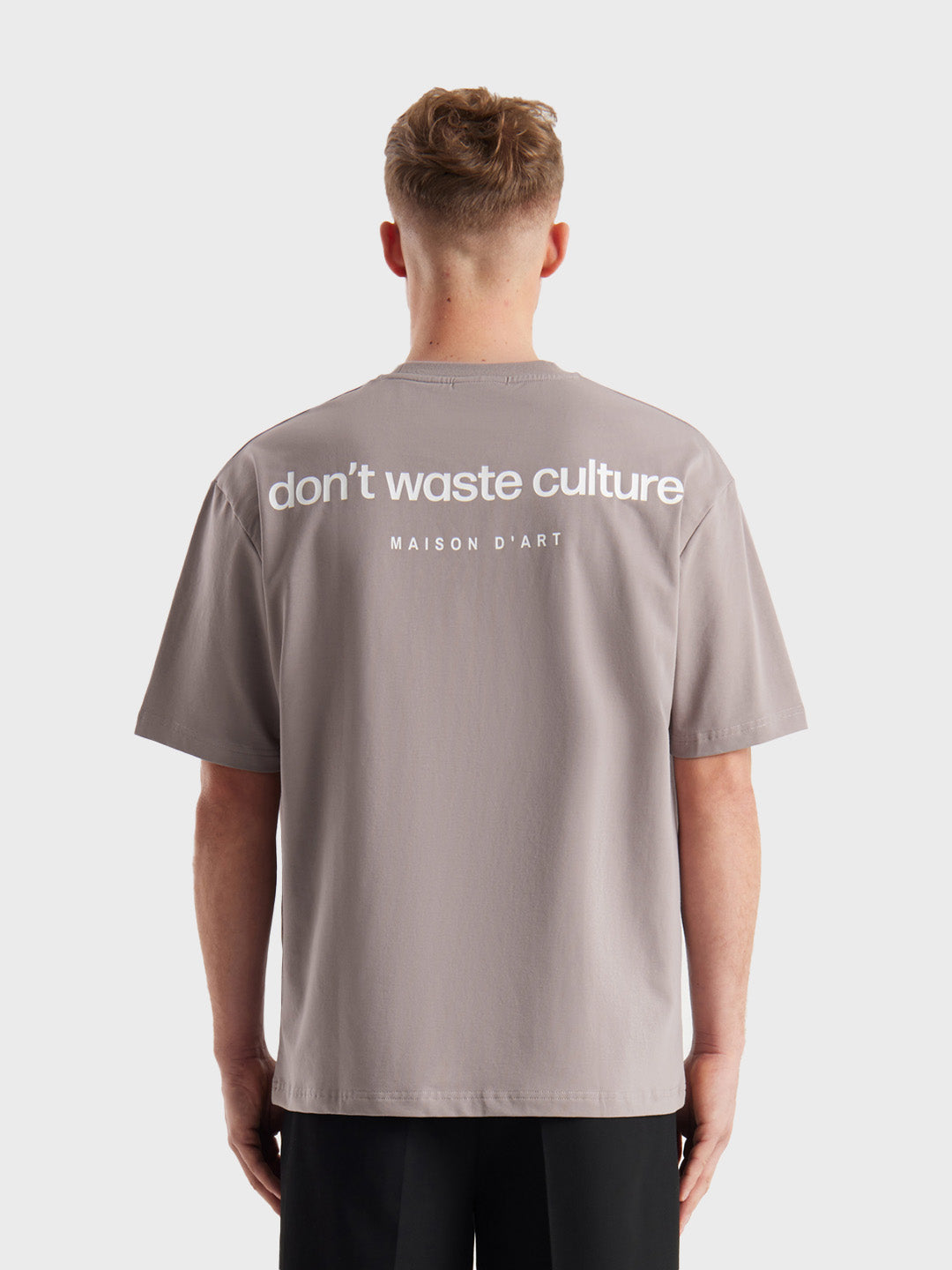 Model draagt Don't Waste Culture Cleo T-Shirt in Warm Grey, achterkant met rugprint