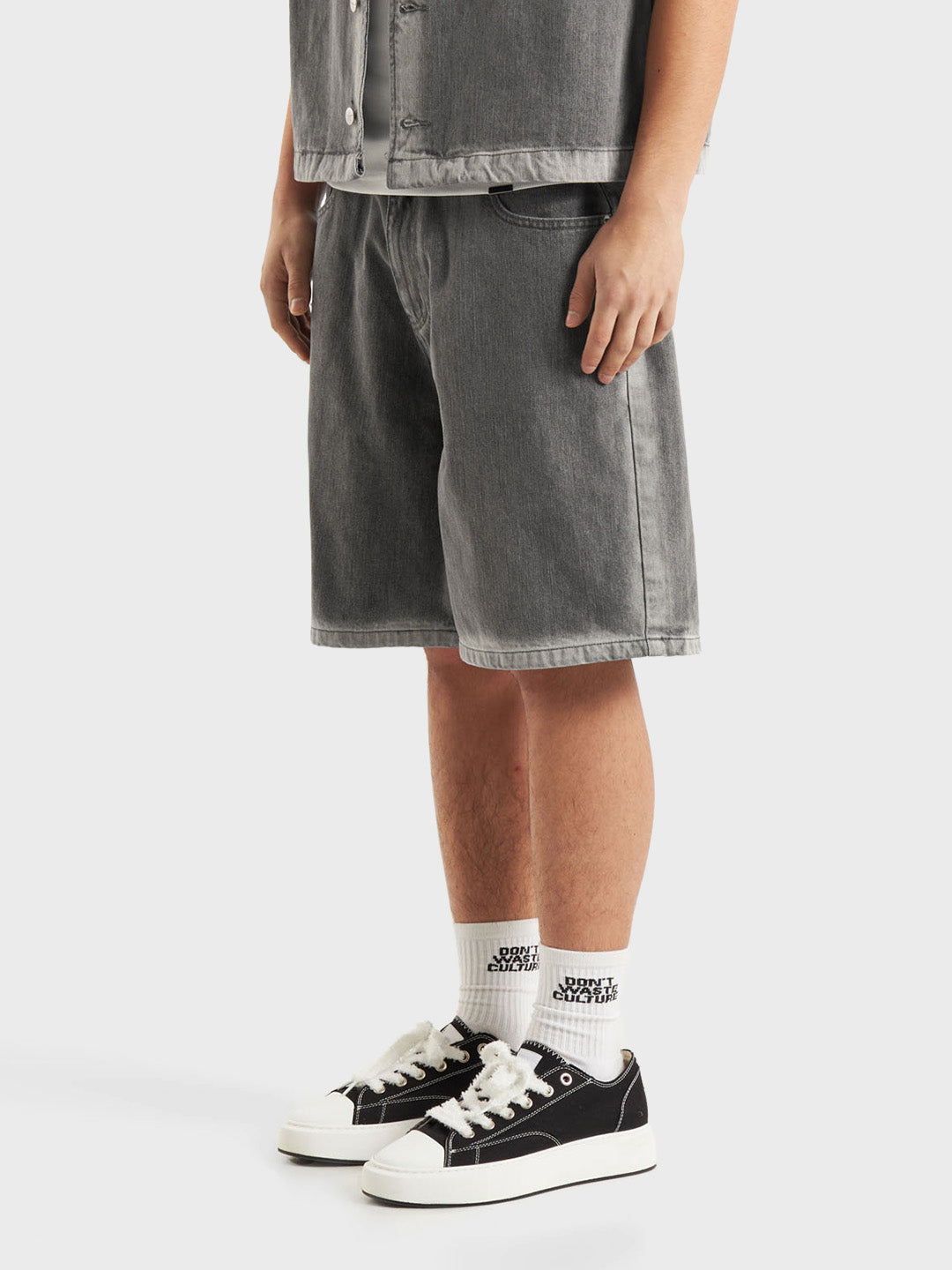 Model draagt DWC Fyori Denim Shorts Grey – schuin vooraanzicht