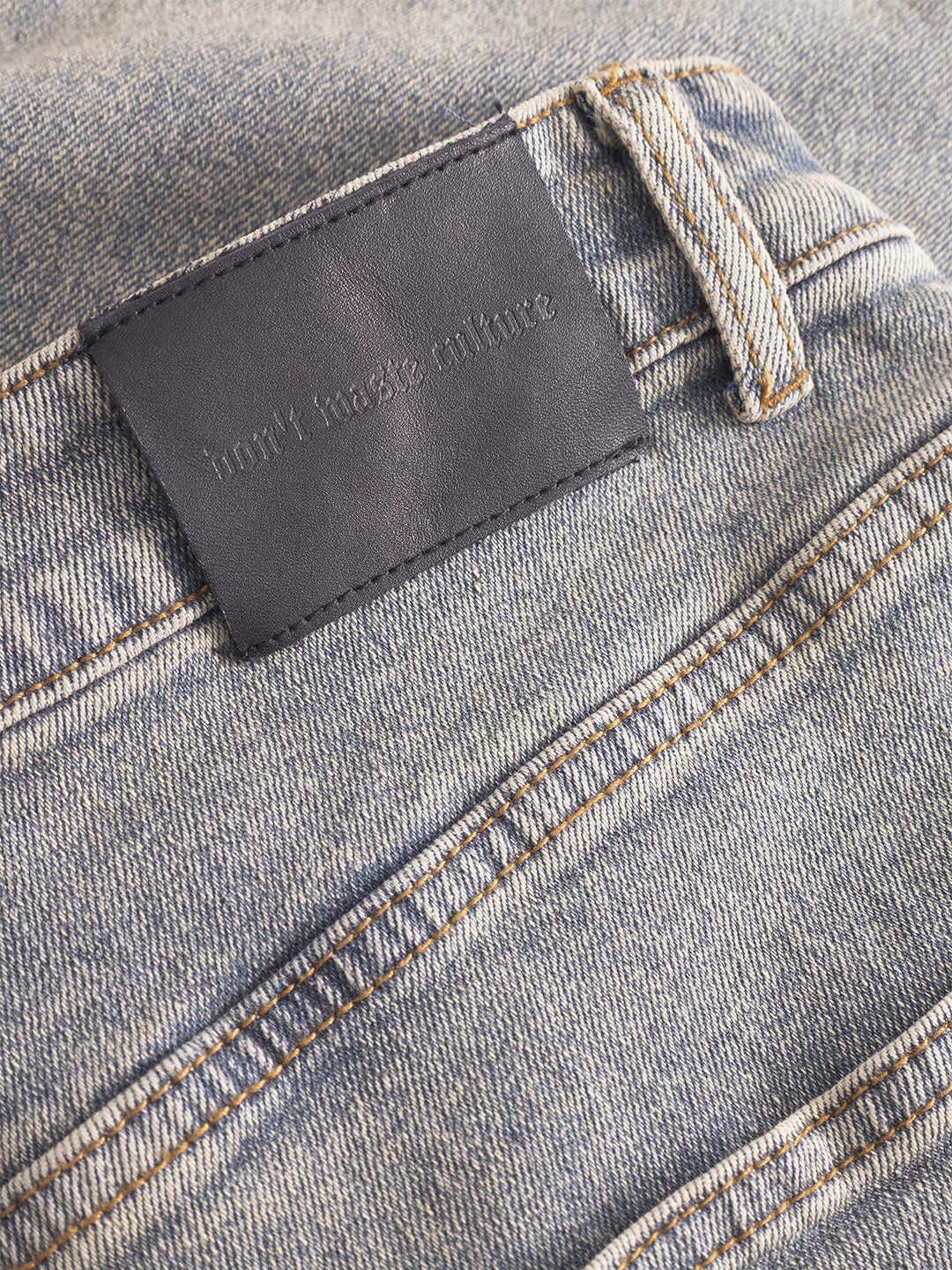 Close-up van de denimstof en leren DWC-patch bij de taille.