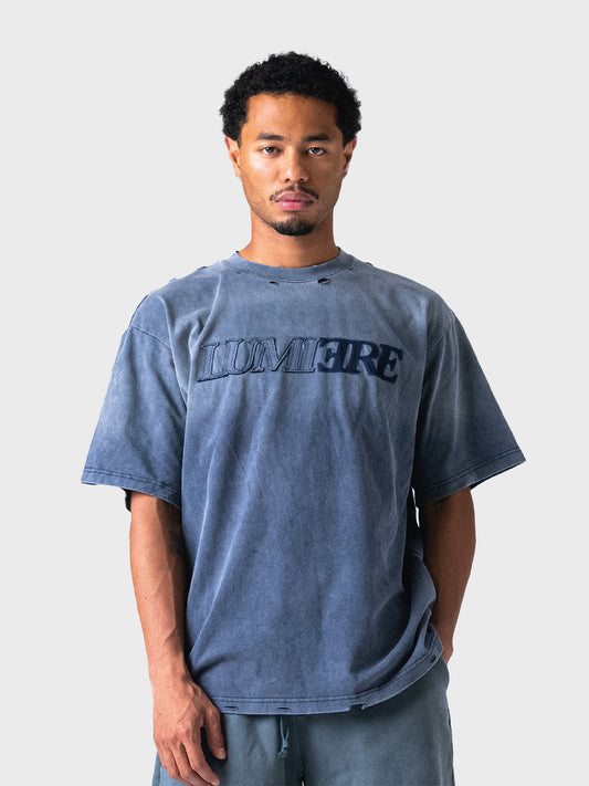 Model draagt Lumi3re Fade Logo T-Shirt in Washed Blue