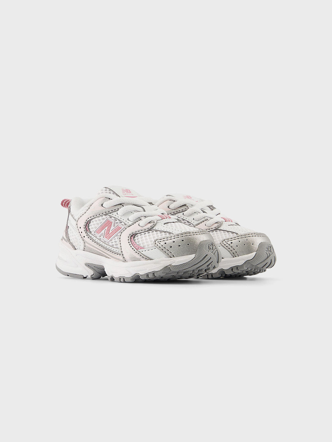 Schuin vooraanzicht van de witte New Balance 530 kinderschoen met roze accenten