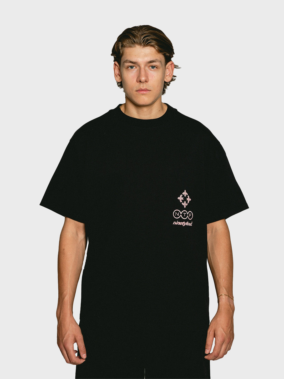 Model draagt Ninetyfour FBF Soft Force T-Shirt Black, voorkant met roze camo Ninetyfour graphic