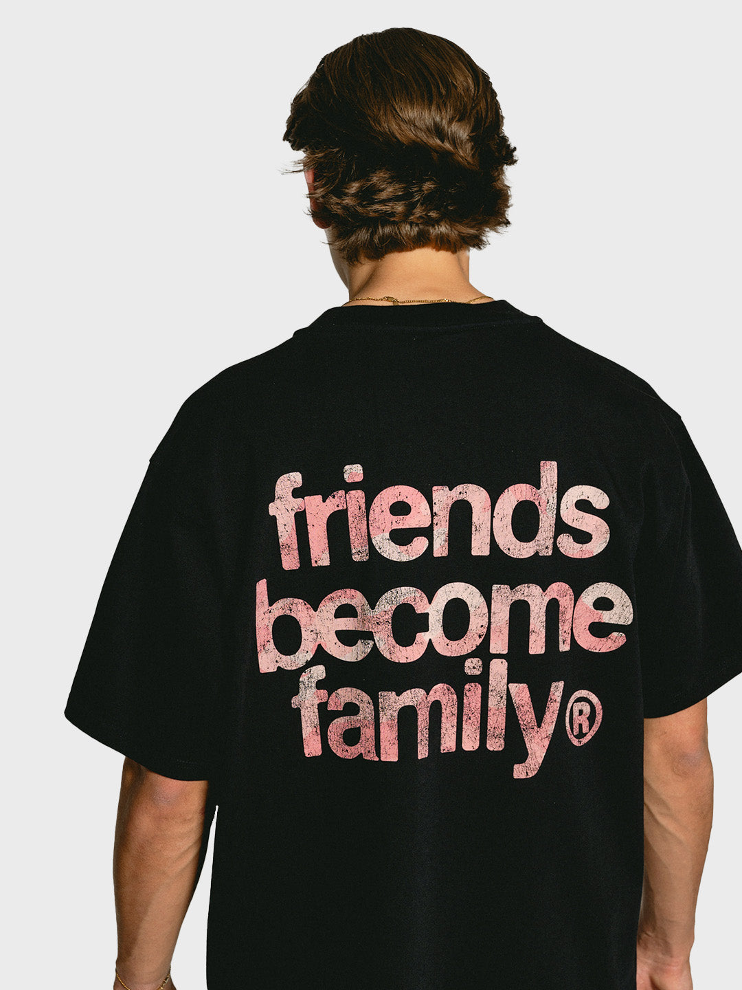 Model draagt Ninetyfour FBF Soft Force T-Shirt Black, achterkant met roze camo 'Friends Become Family' print
