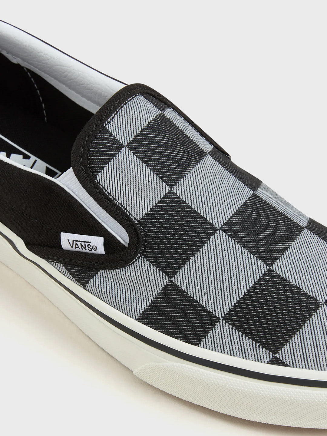 Close-up van checkerboard canvas en elastisch zijpaneel van de Vans Slip-On sneakers