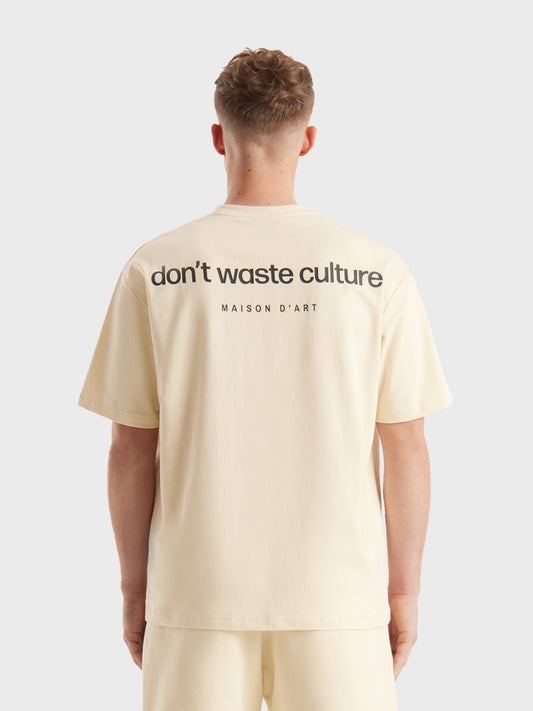Model draagt Don’t Waste Culture Cleo T-shirt in beige, rugzijde zichtbaar met grote graphic