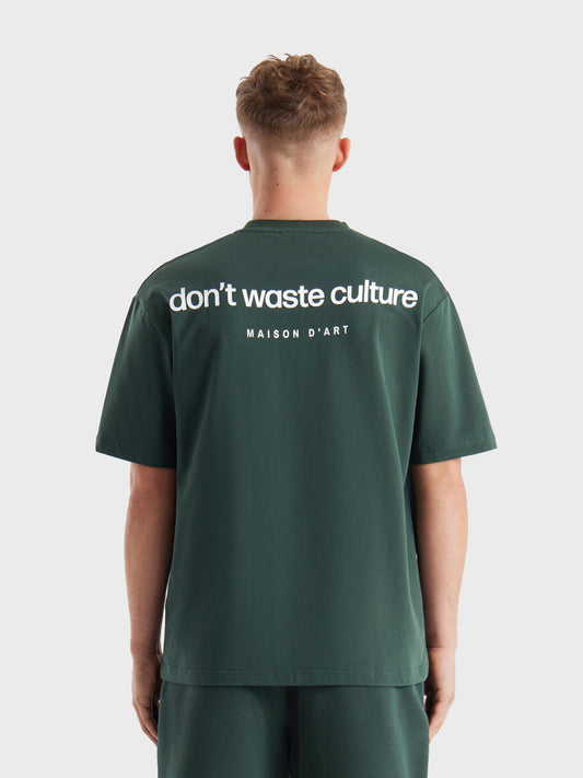 Model draagt Don’t Waste Culture Cleo T-shirt in Dark Green, rugzijde zichtbaar met grote graphic