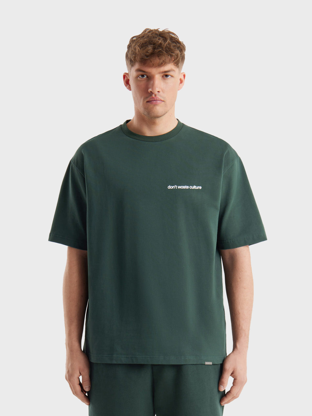 Model draagt Cleo T-shirt in Dark Green, met kleine borstbranding