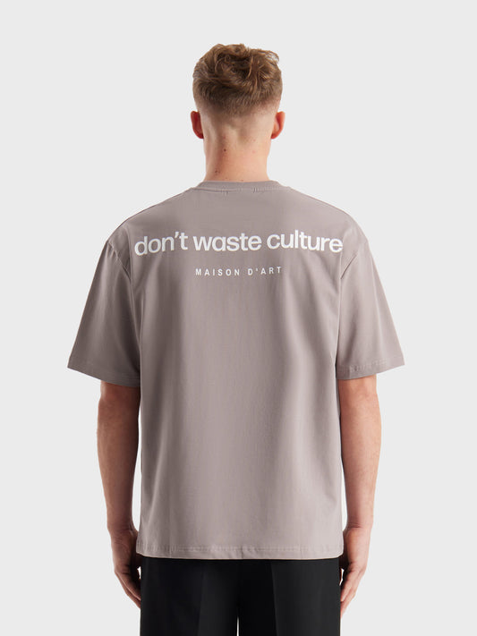Model draagt Don't Waste Culture Cleo T-Shirt in Warm Grey, achterkant met rugprint