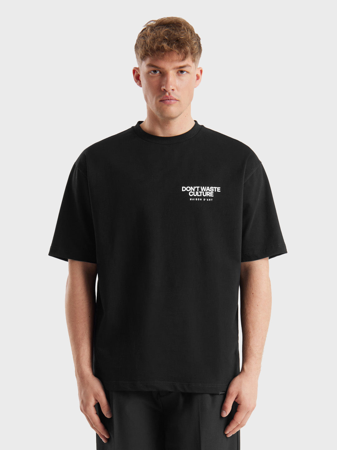 Model draagt het zwarte Don’t Waste Culture Tirion t-shirt met kleine borstprint, front view.