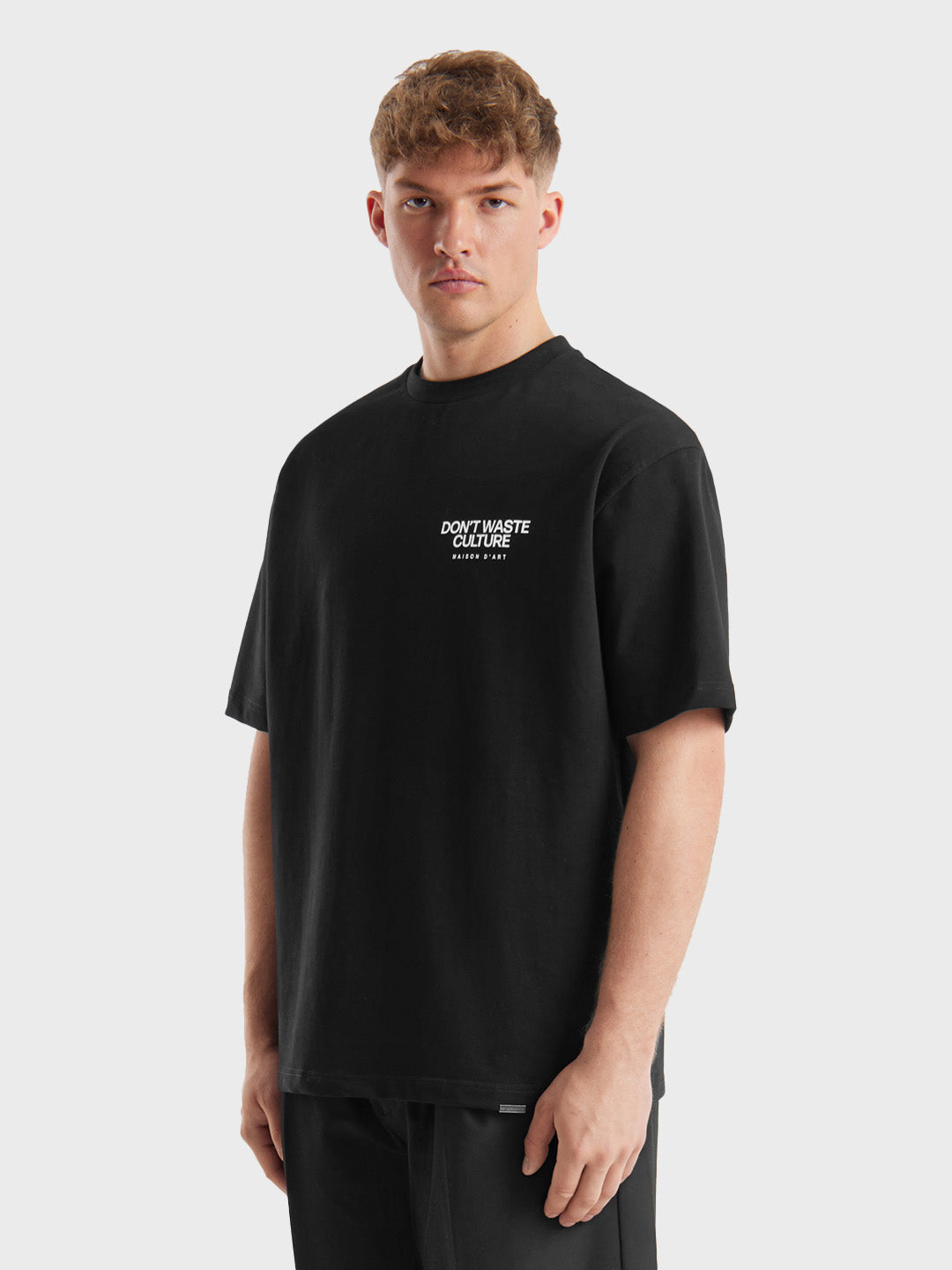 Schuin vooraanzicht van model met het zwarte Don’t Waste Culture Tirion T-shirt.