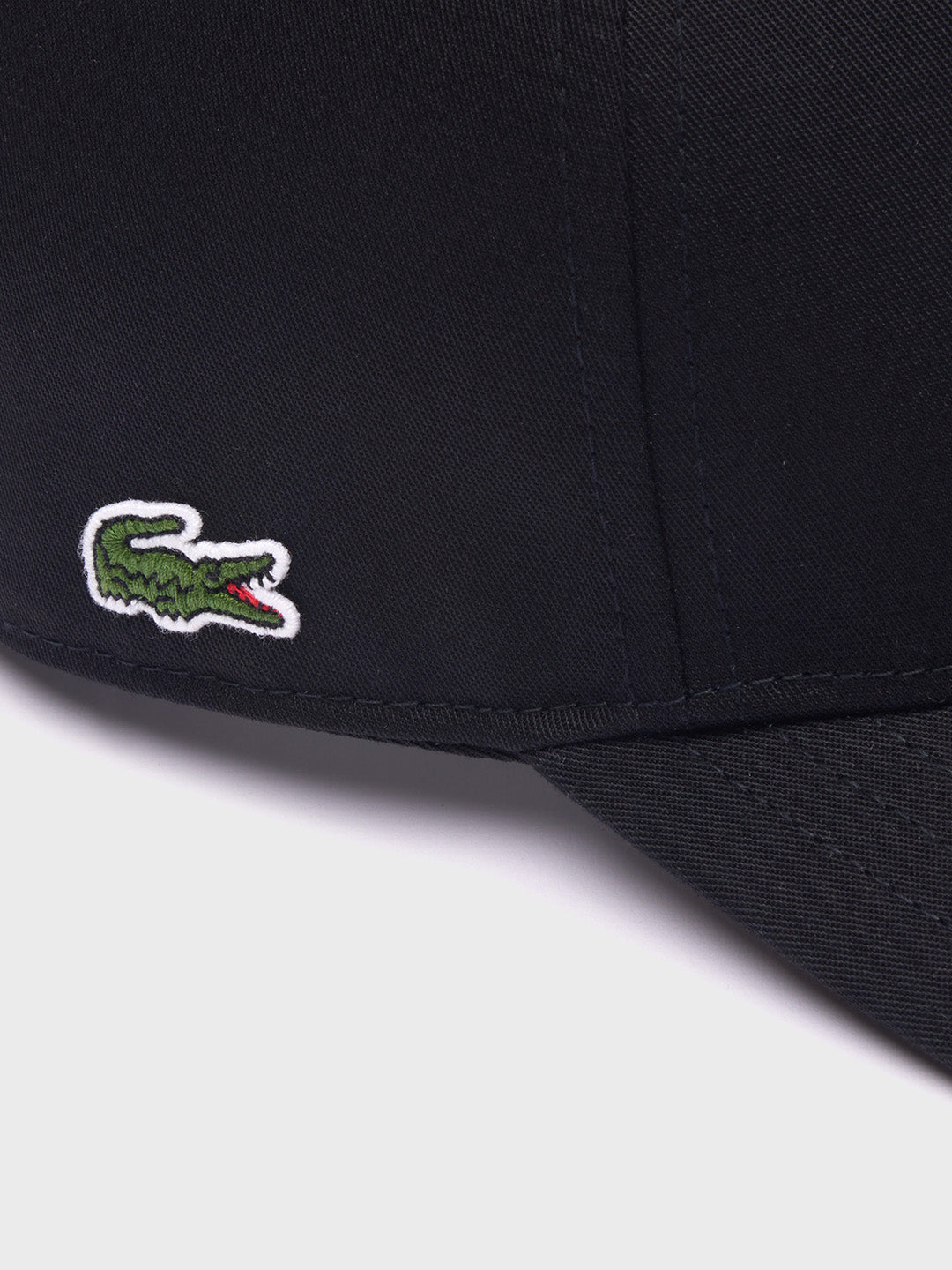 Detail van geborduurde Lacoste krokodil op de zijkant van de zwarte cap