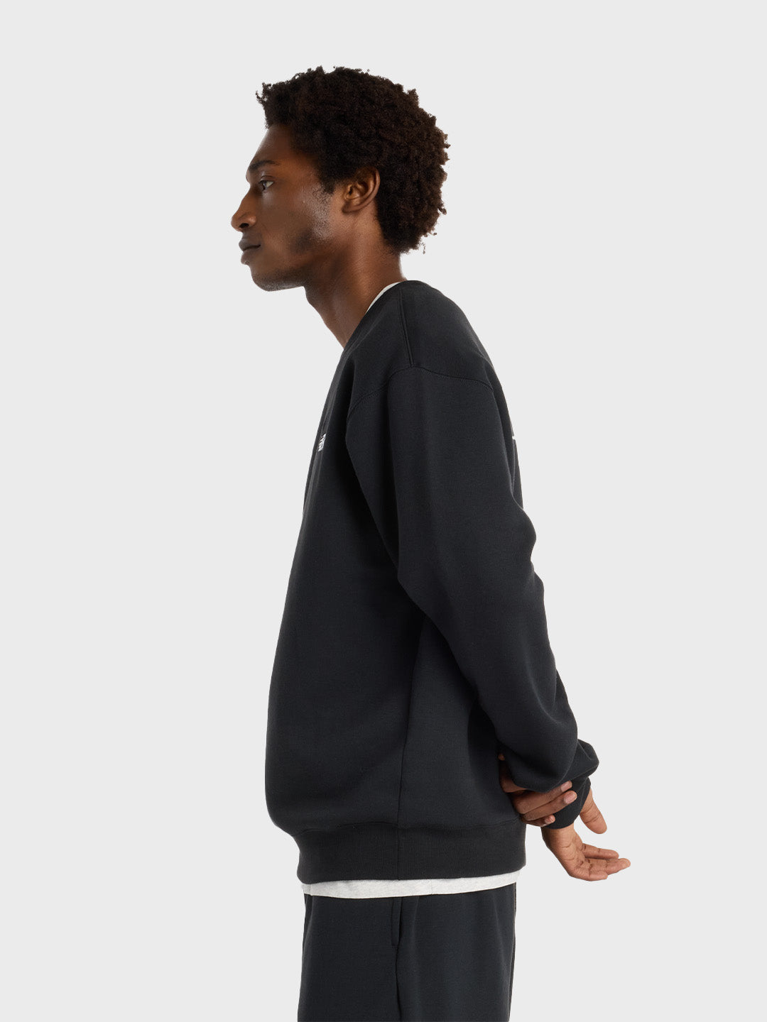 Zijaanzicht van het model met zwarte New Balance sweater