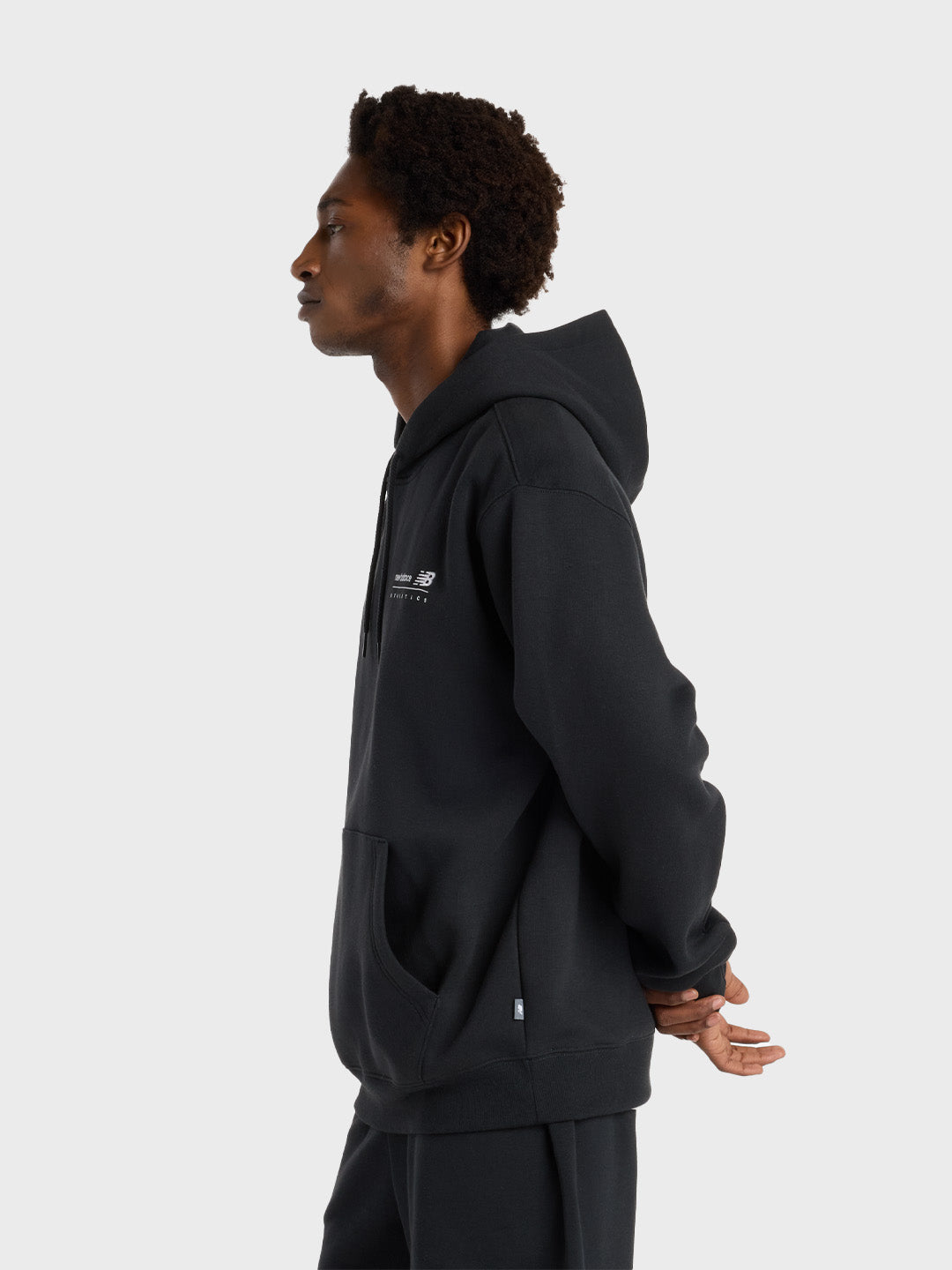 Zijaanzicht van het model met de zwarte New Balance hoodie