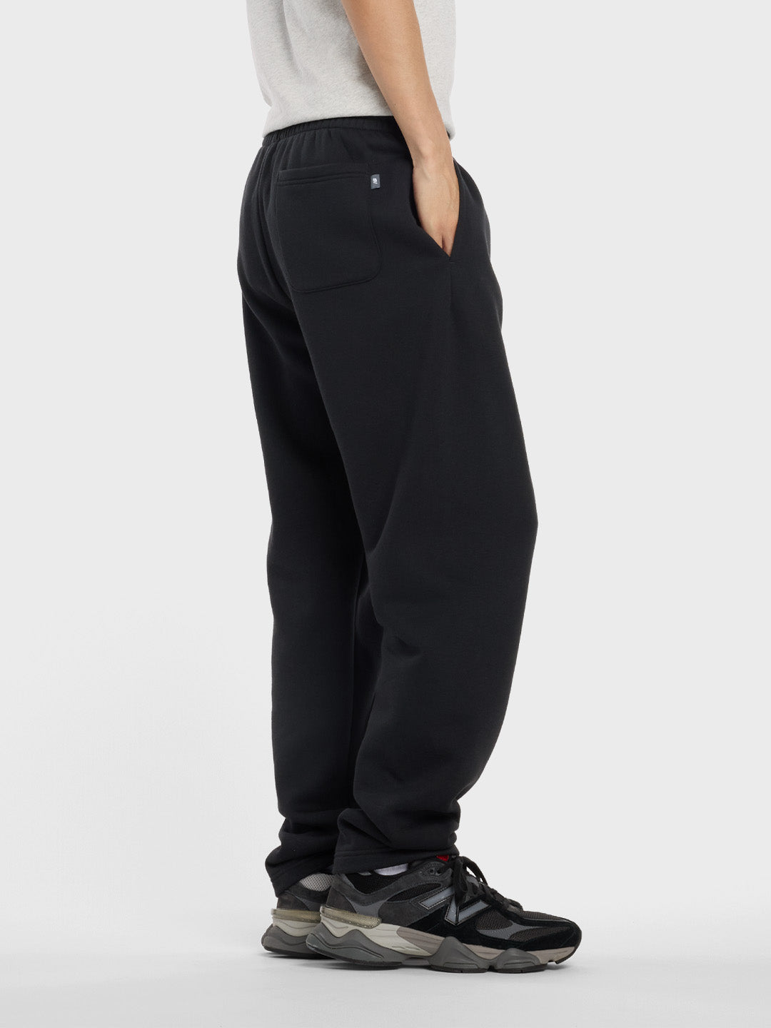Zijaanzicht van het model in zwarte New Balance jogger