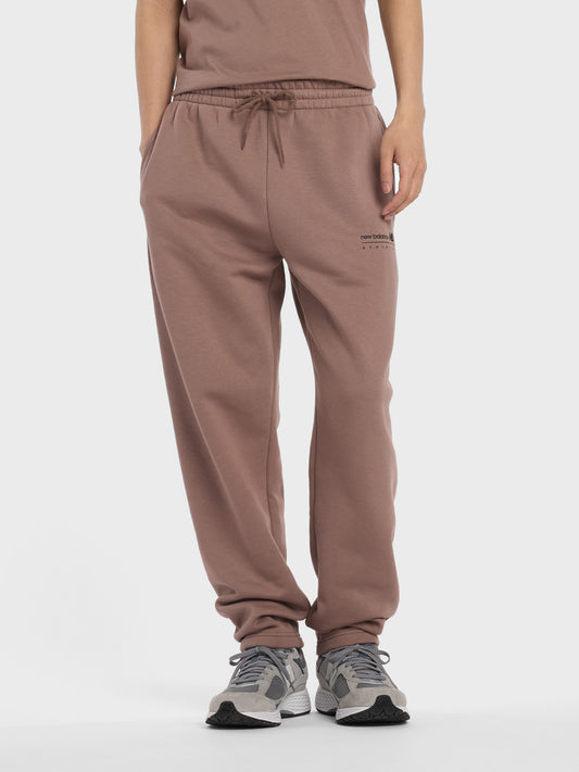 Model draagt New Balance Linear Graphic Sweatpants Earth Shadow vooraanzicht