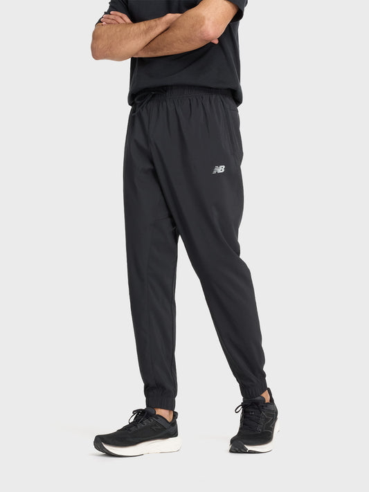 Model draagt de New Balance Sport Essentials Trackpants in zwart, vooraanzicht