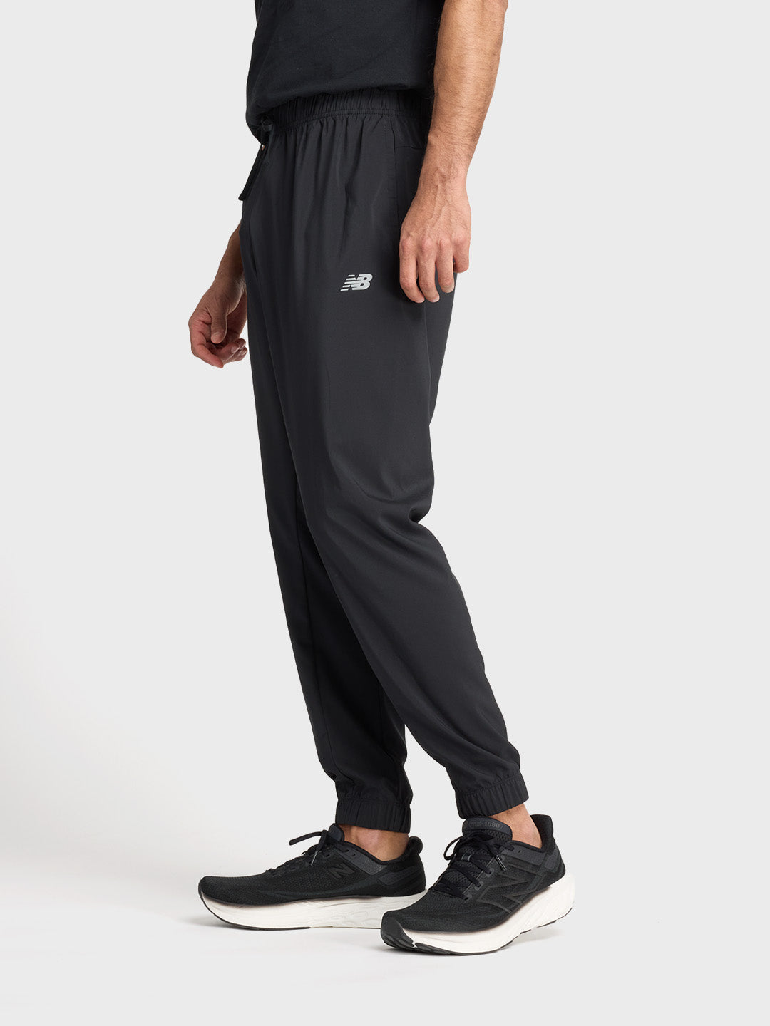 Schuin vooraanzicht van de zwarte New Balance trackpants aan model