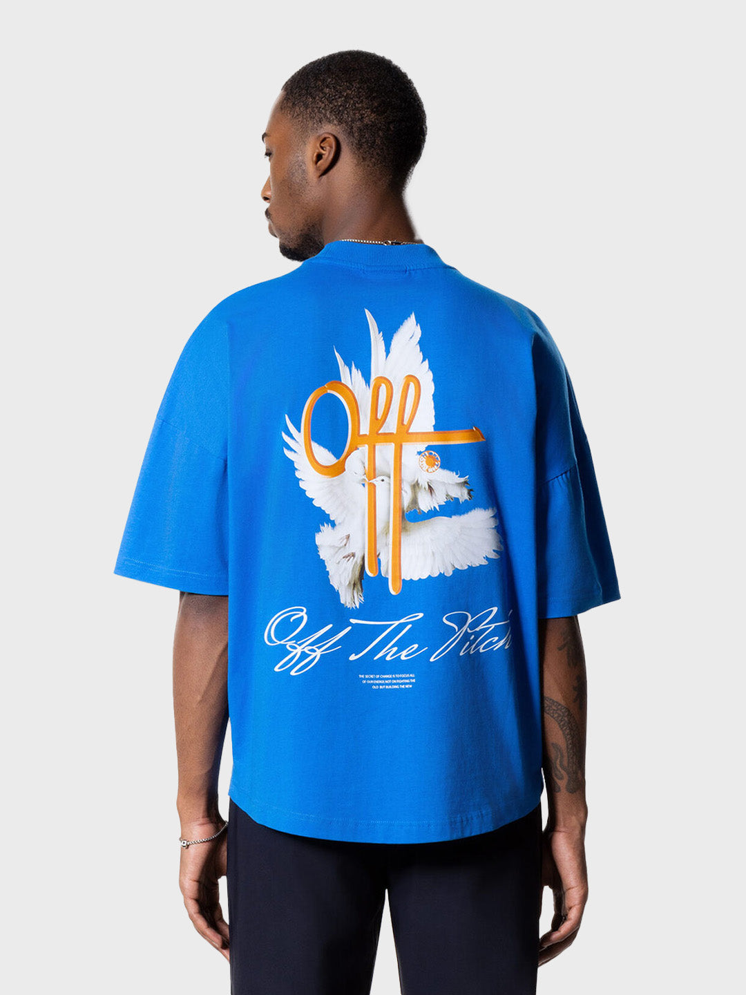 Model draagt Off The Pitch Rebirth T-Shirt in blauw met grote rugprint – achteraanzicht