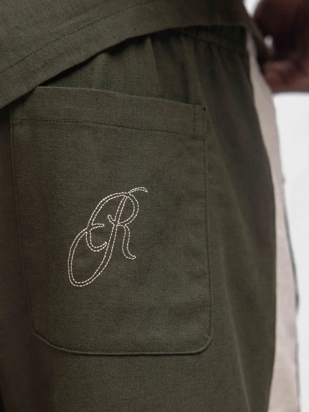 Close-up Rivero geborduurd logo op achterzak van groene short