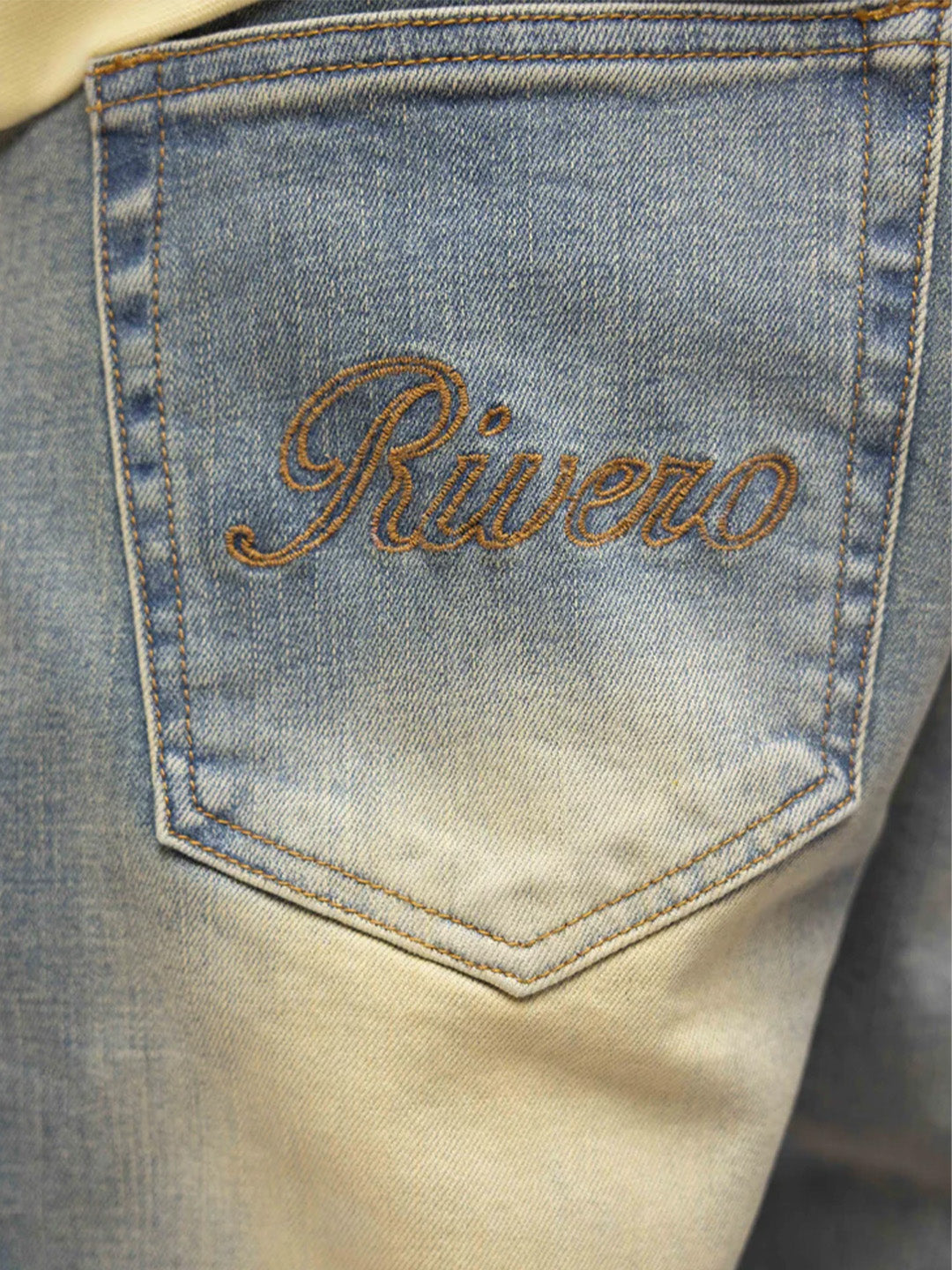 Close-up geborduurd Rivero-logo op de achterzak van de Segmented Washed Jeans