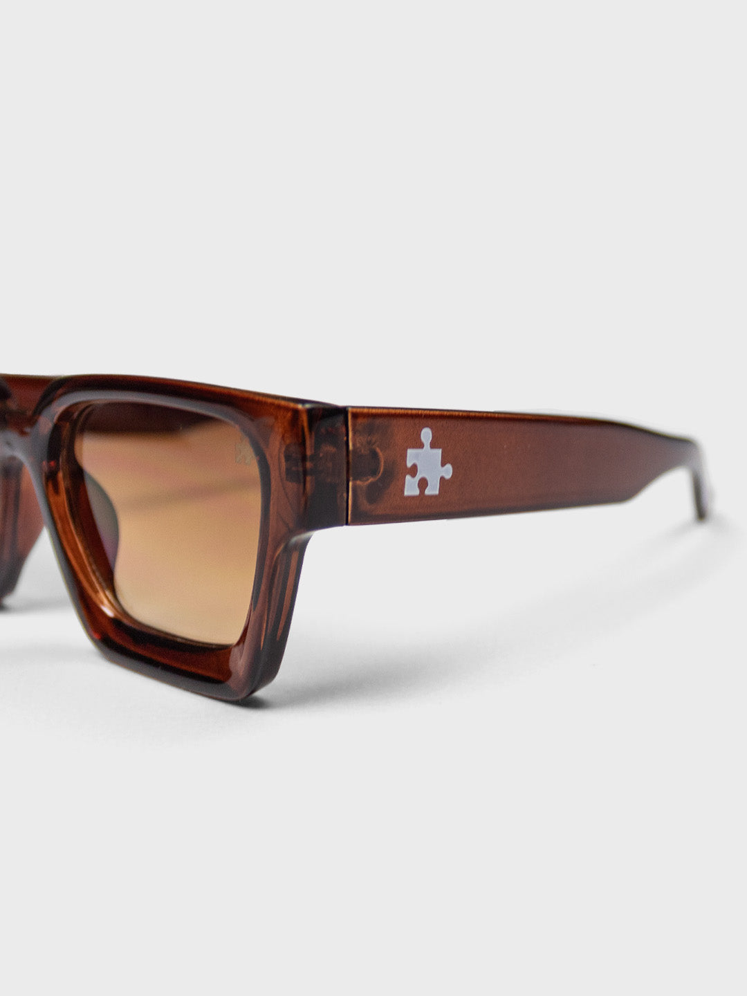 The Missing Piece Classic Shades Brown - close-up puzzle piece logo